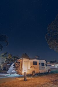 a camper parked next to a tree at night
