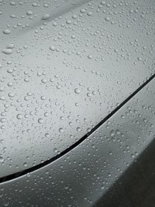 Water droplets on a metallic gray car hood.